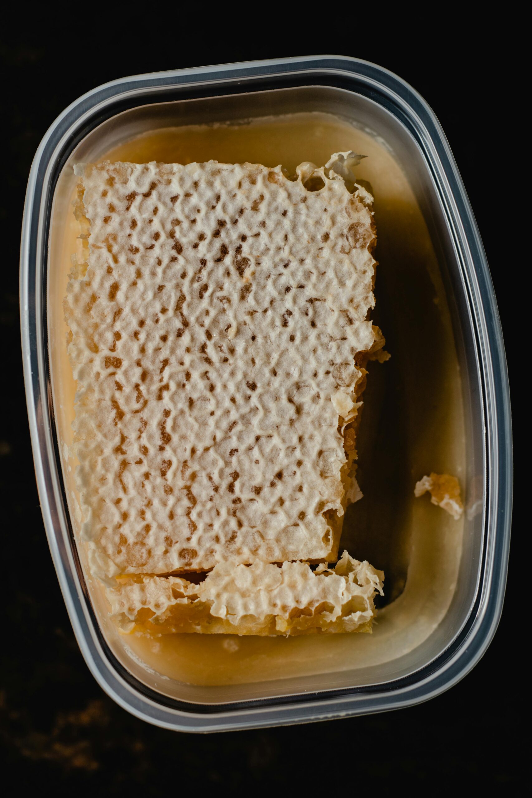 Top view of a fresh honeycomb in a plastic container, sweet and nutritious.
