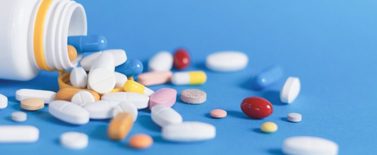 Different color and size pills coming out of pill bottle.